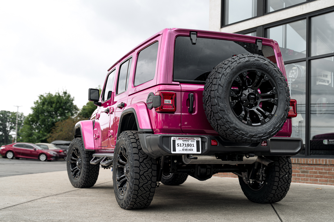 Pink Jeep Wrangler with a ReadyLift lift kit, Fuel wheels, N-Fab running boards, a Westin front bumper, a Superwinch winch, and a Curt hitch.