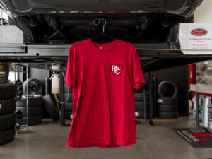 Red pickups plus cars t shirt with black shield logo on left breast